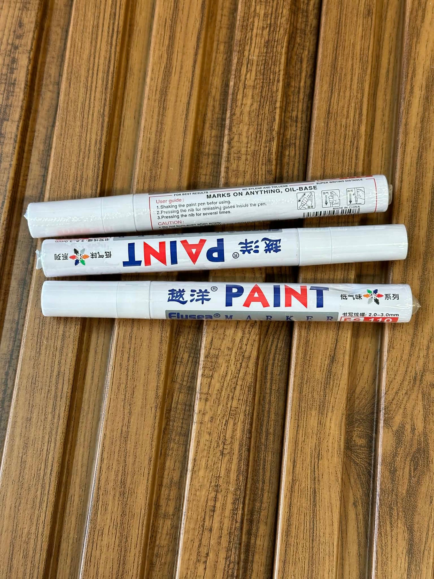 Three paint markers on a wooden surface