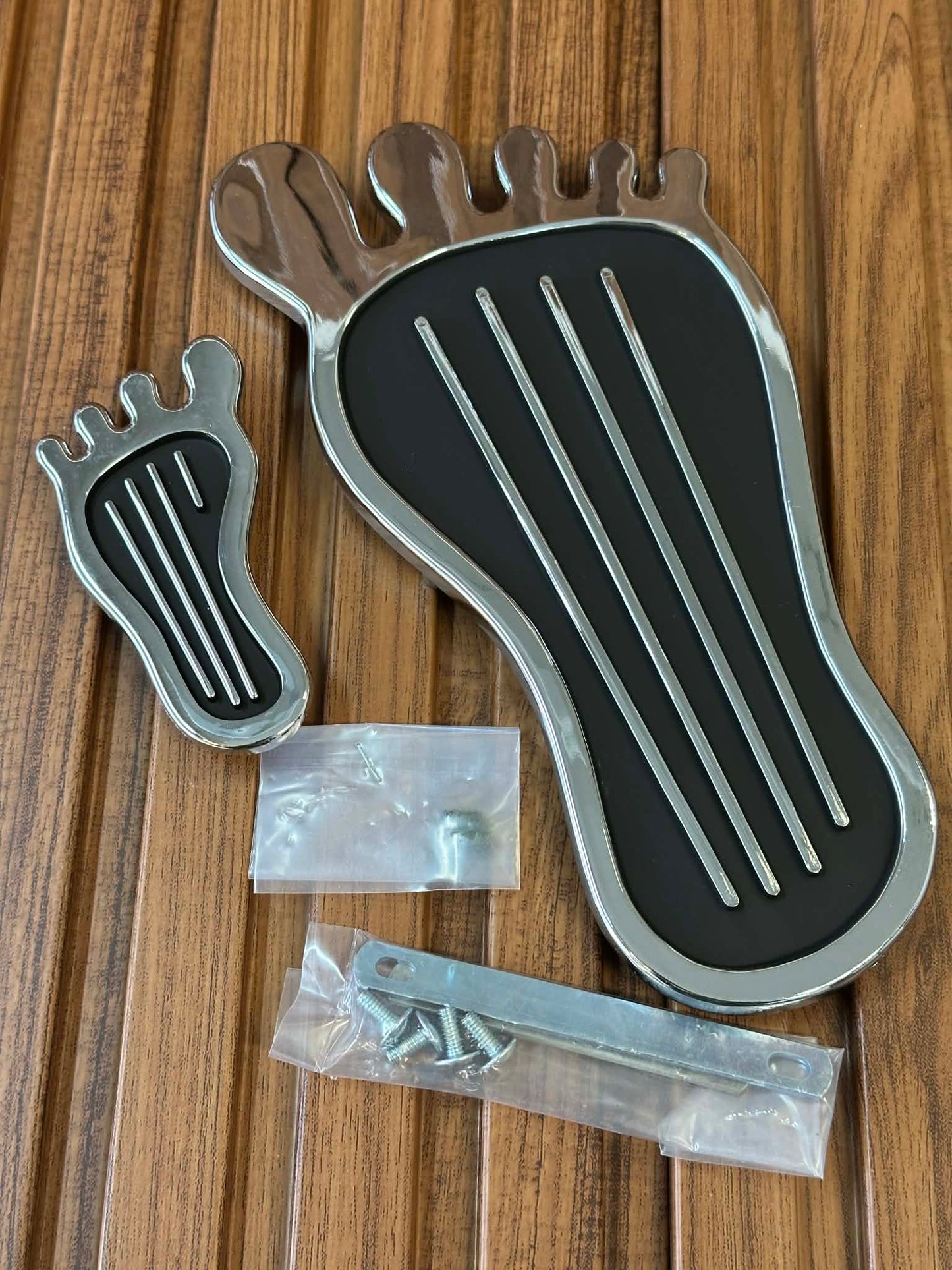 Metallic foot-shaped object with screws on a wooden surface