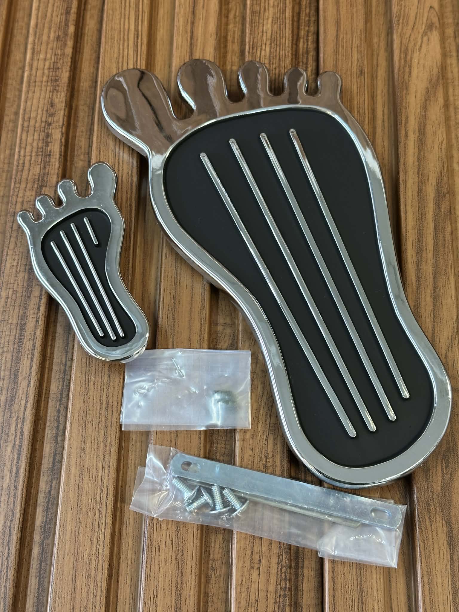 Metallic foot-shaped object with screws on a wooden surface