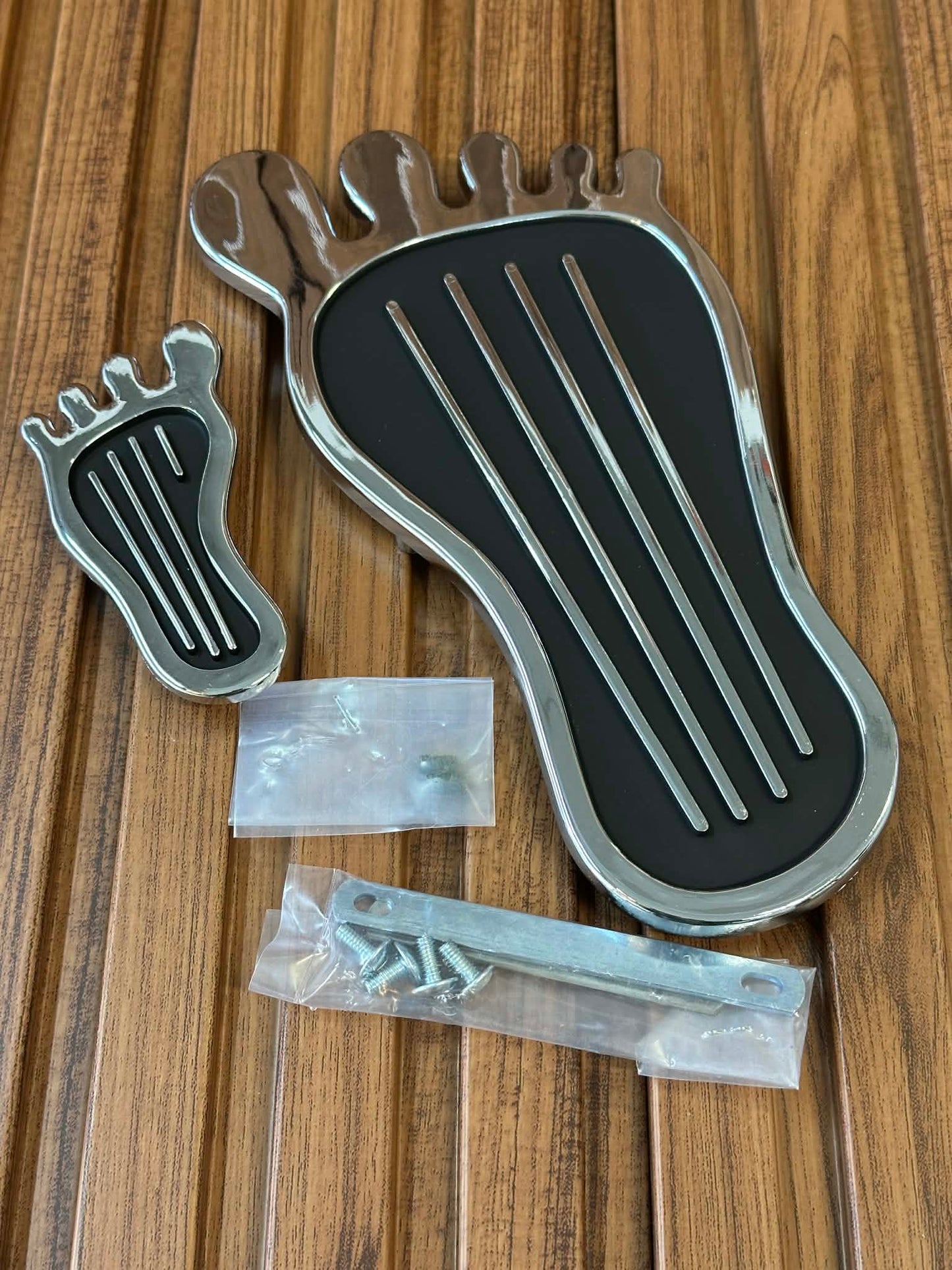 Metallic foot-shaped object with screws on a wooden surface