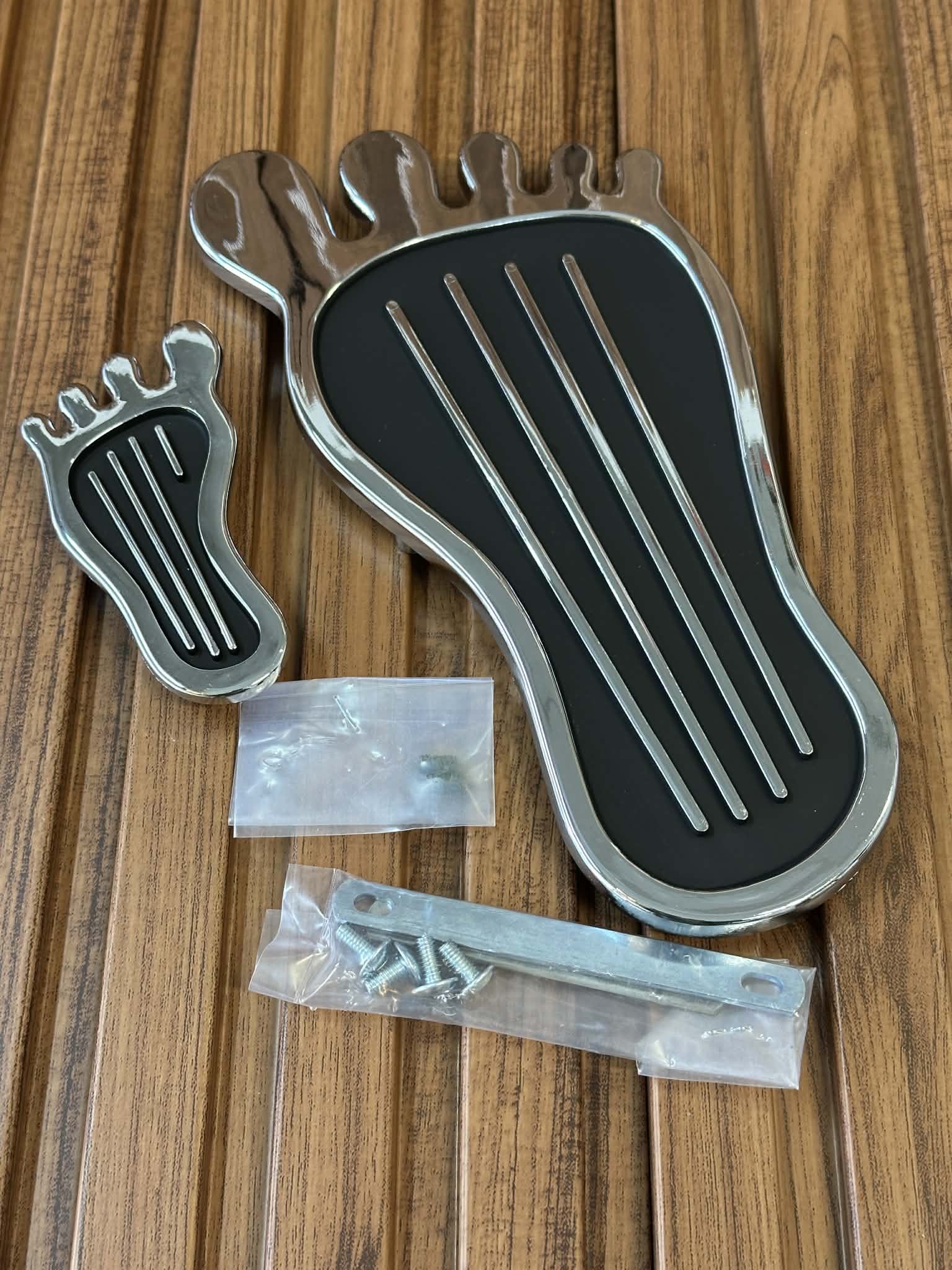 Metallic foot-shaped object with screws on a wooden surface