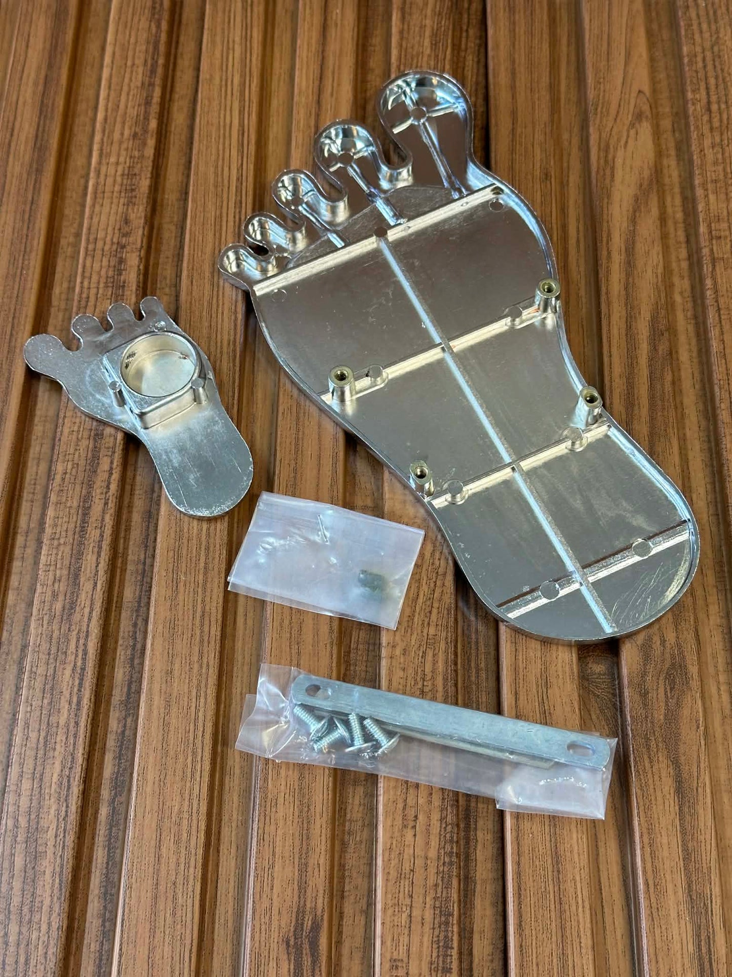 Metal foot-shaped component with screws on a wooden surface