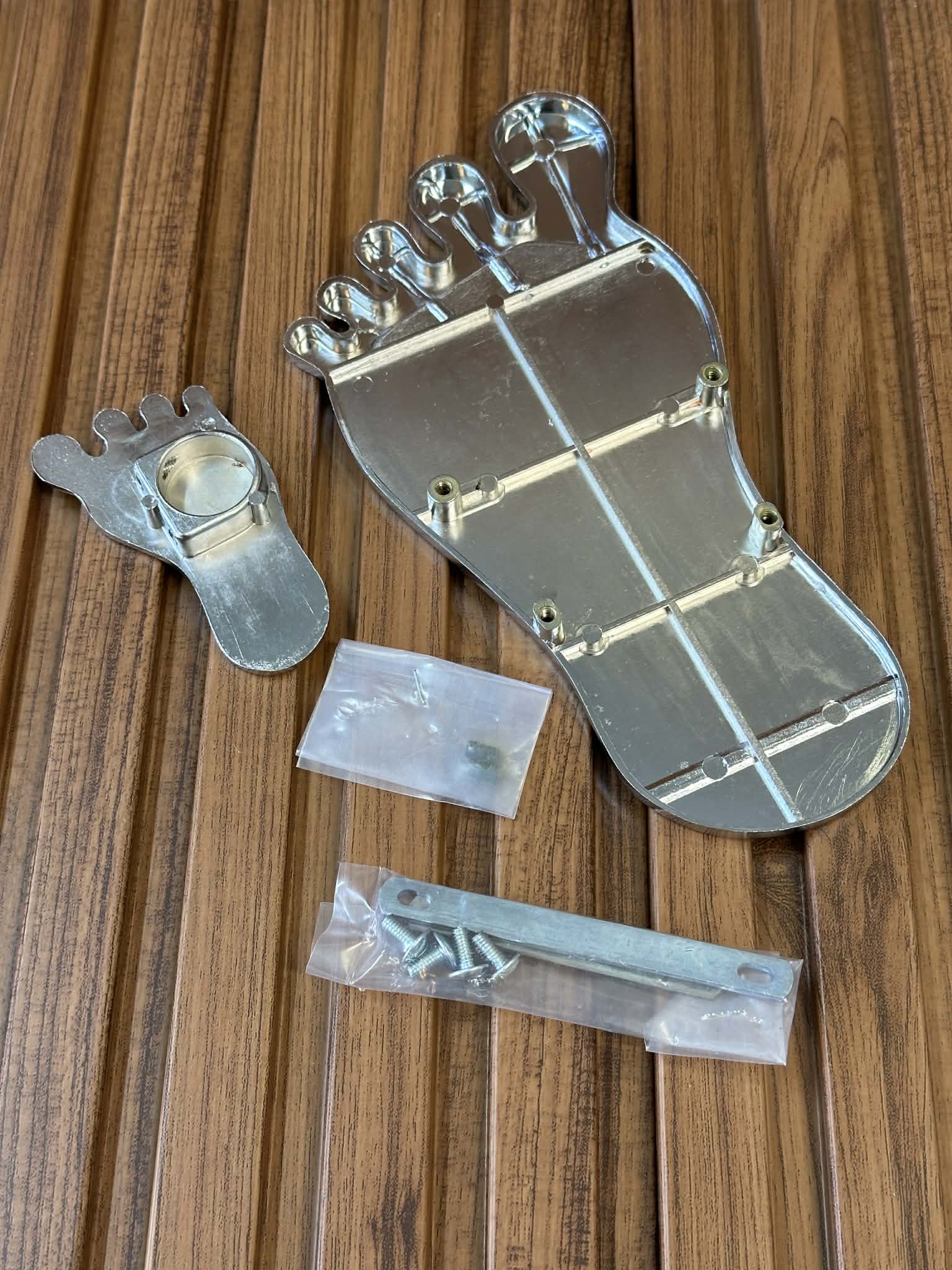 Metal foot-shaped component with screws on a wooden surface