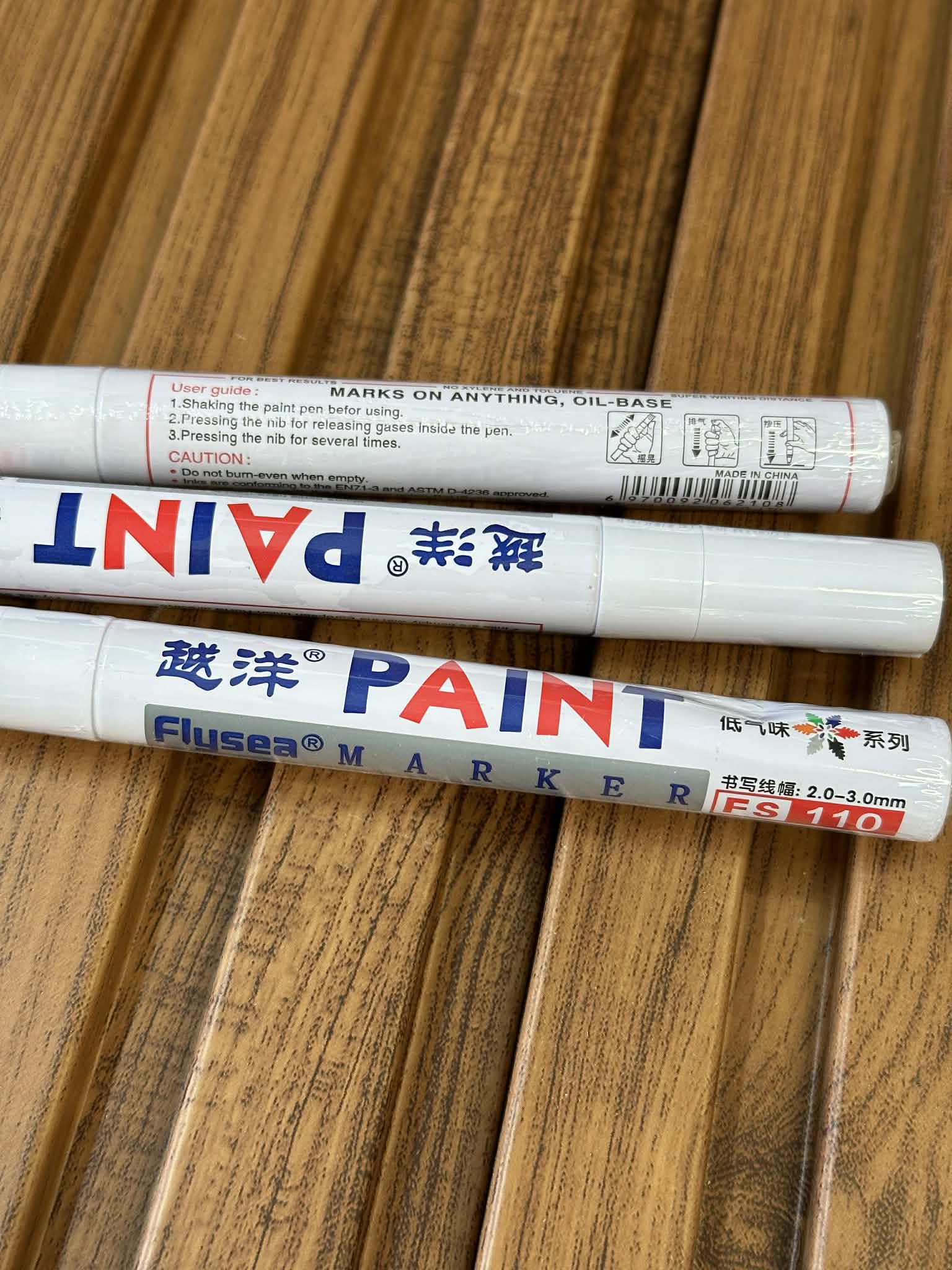 Two paint markers on a wooden surface