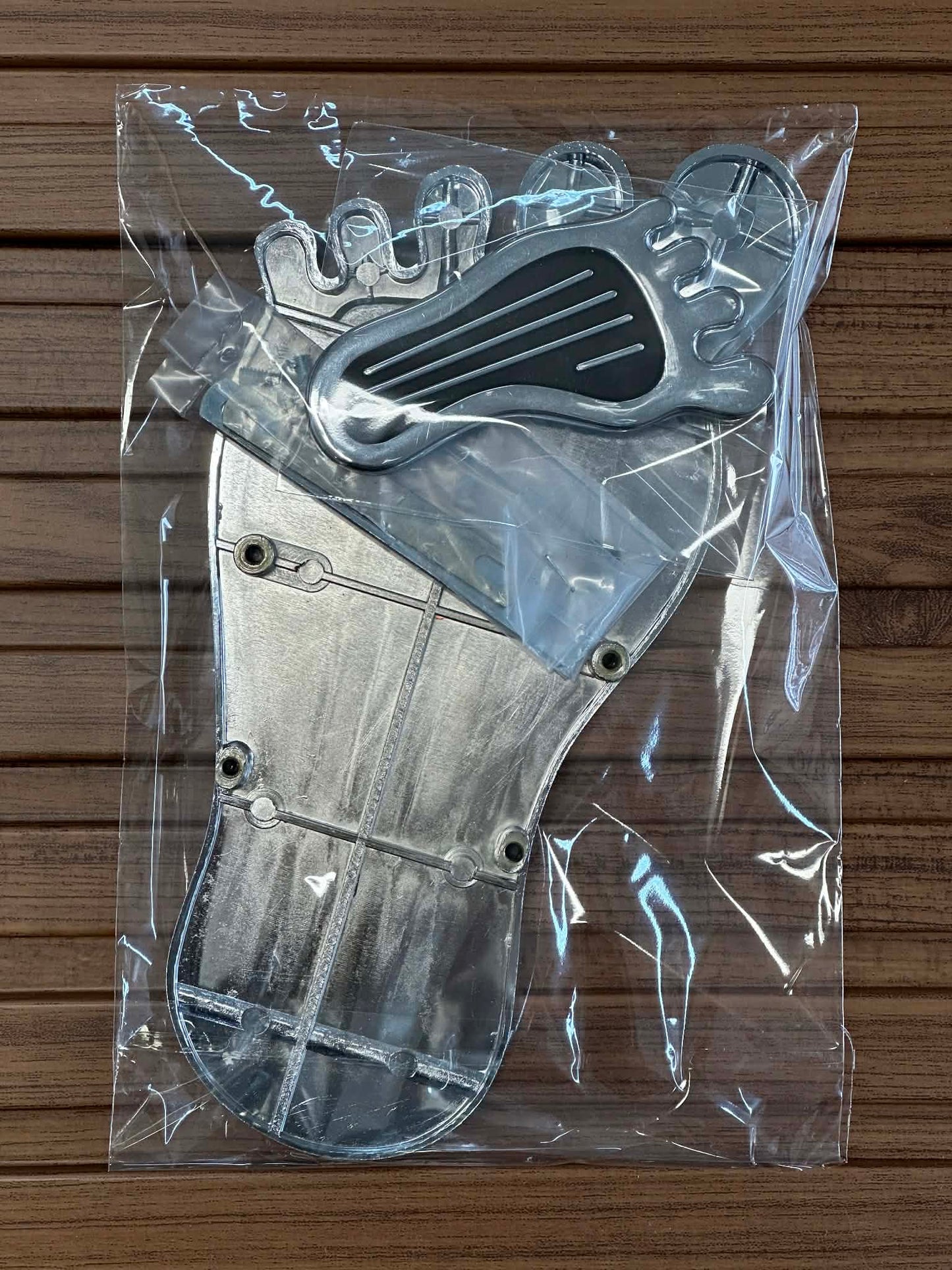 Metallic glove model in clear plastic packaging on a wooden surface