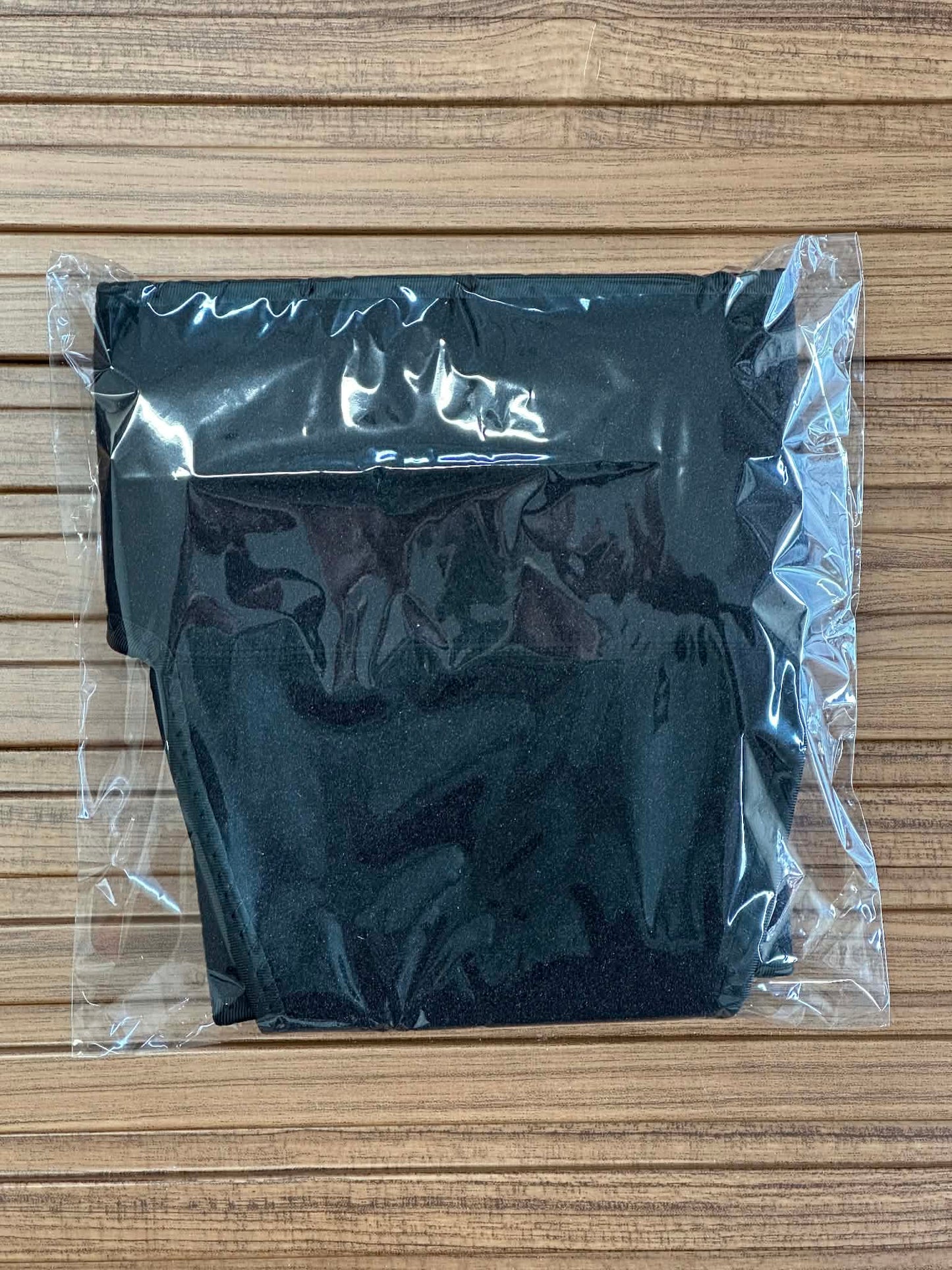 Black fabric in a clear plastic bag on a wooden surface