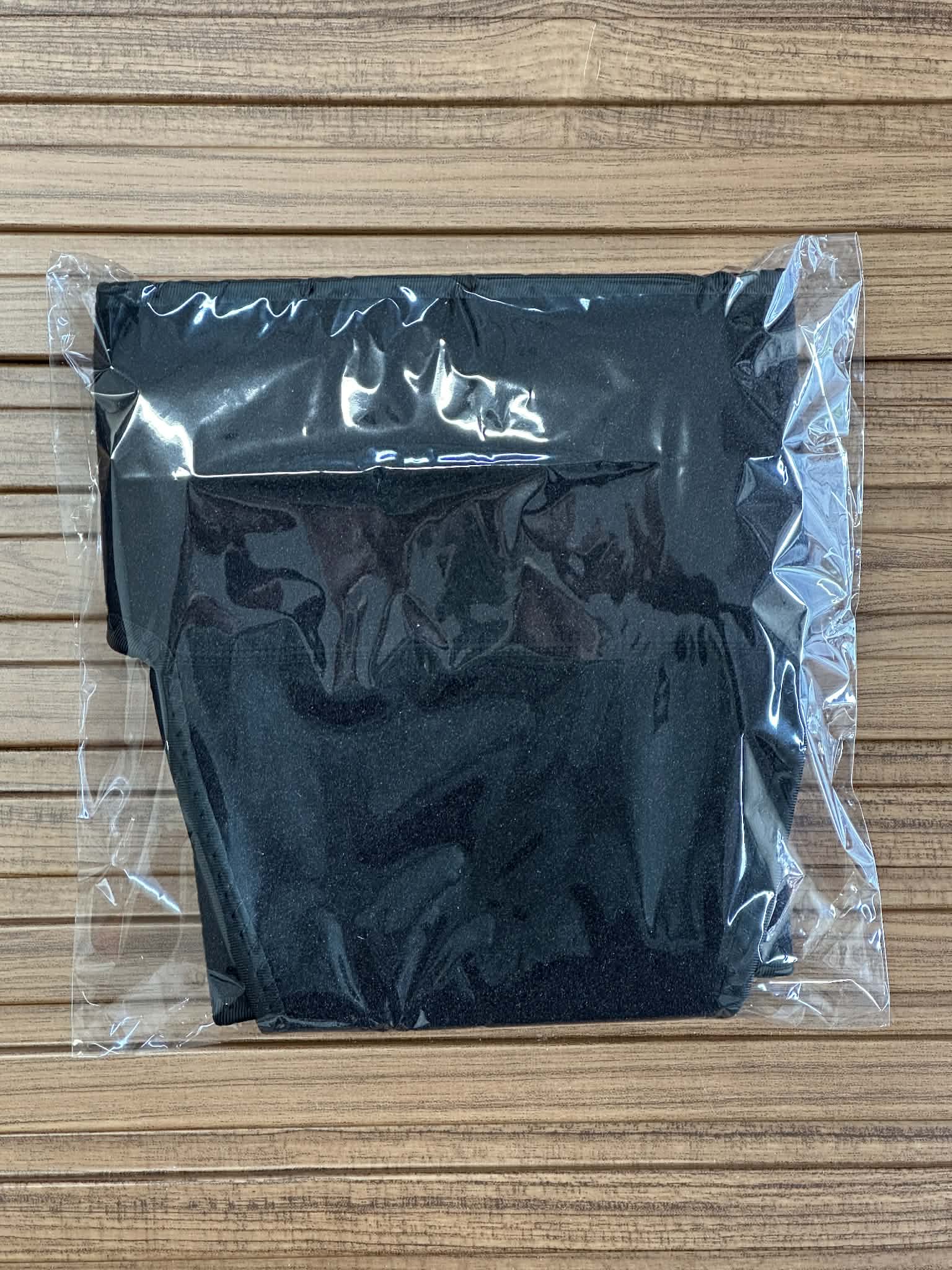 Black fabric in a clear plastic bag on a wooden surface