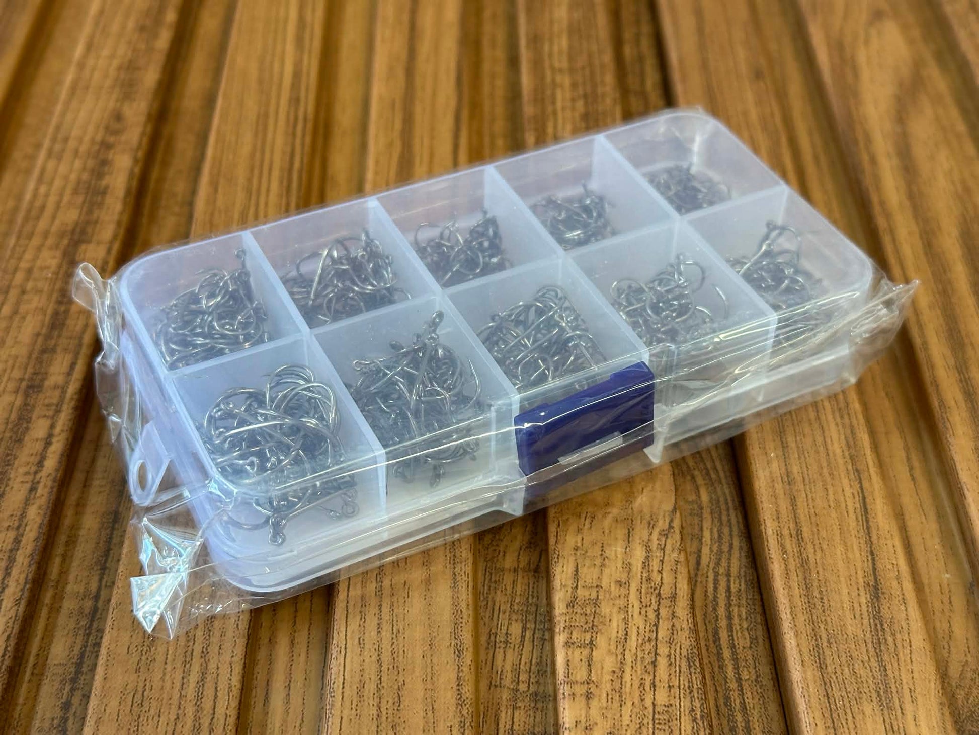 Clear plastic container with small metal hooks on a wooden surface
