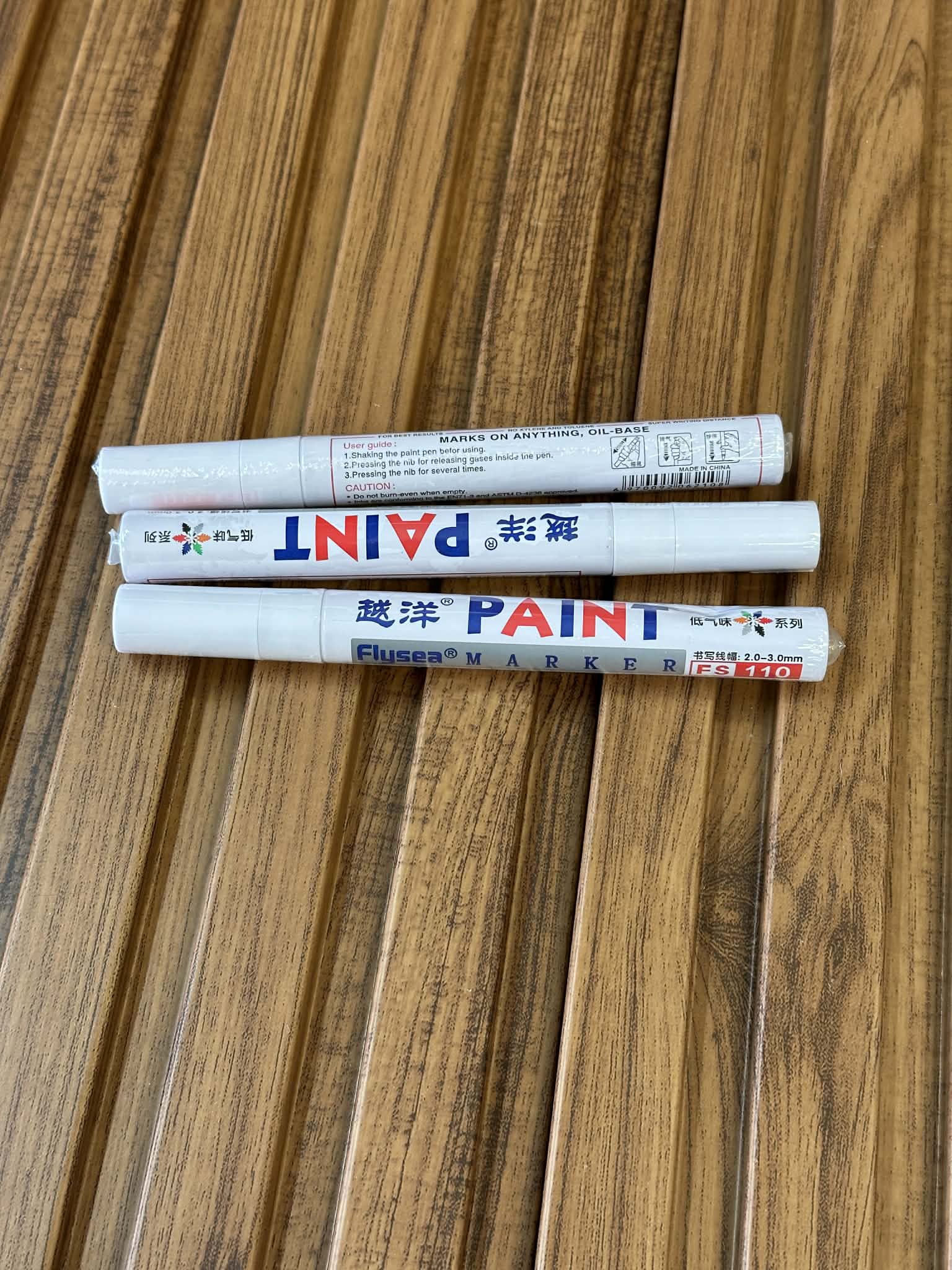 Three paint markers on a wooden surface