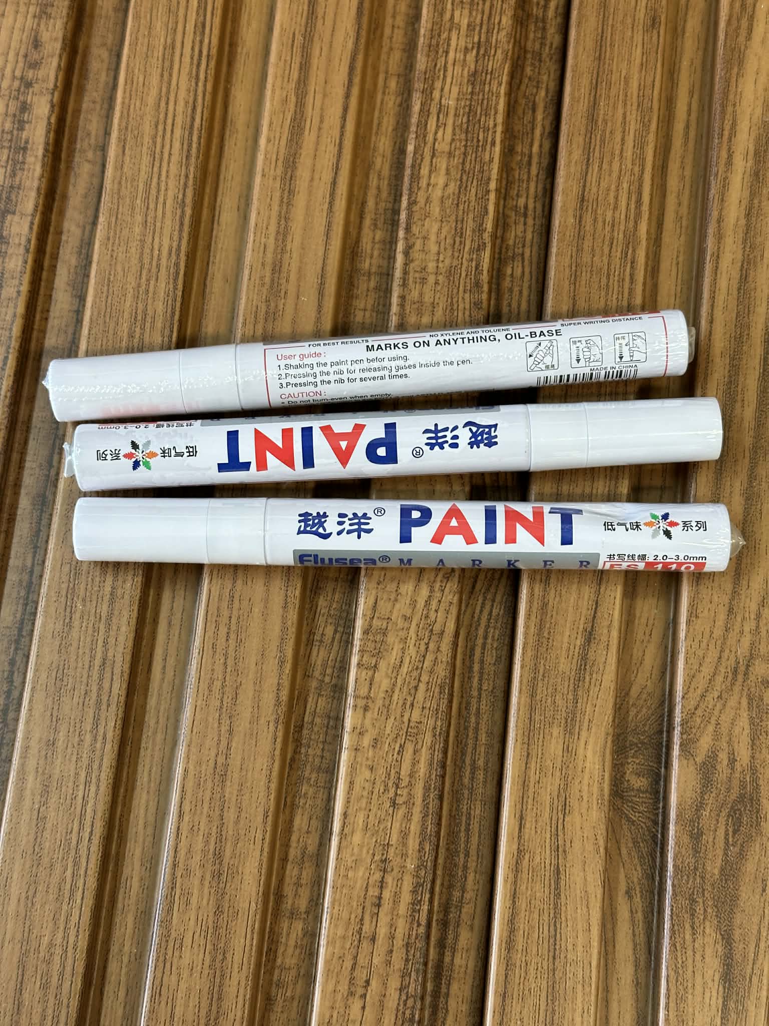 Three paint markers on a wooden surface